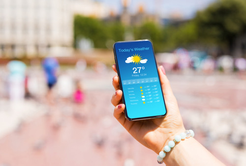Person holding phone with weather app open