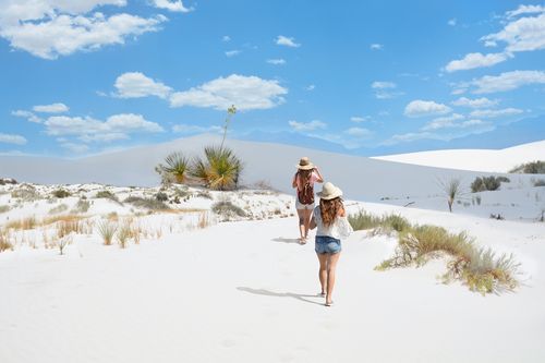 Two girls walking through the sand at White Sands National Monument, New Mexico.