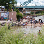 Families play in the river at Confluence Park in Denver