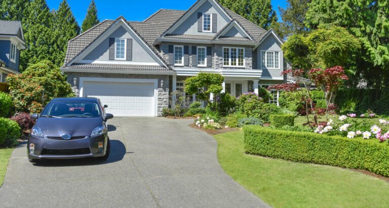 Suburban house with double garage and car parked on concrete driveway.