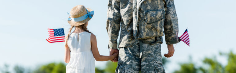 panoramic shot of patriotic child and man in military uniform holding hands and american flags