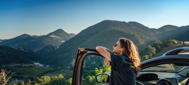 Young beautiful woman traveling by car in the mountains, summer vacation and adventure