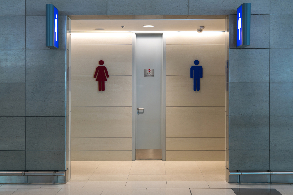 Front view of public restroom or toilet with man and women signs on marble wall.