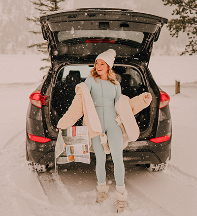 girl laughing in snow outside car 