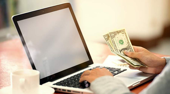 Guy holding money at a laptop computer