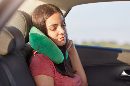 Female passenger sleeps in car while rides on long distance, uses small pillow