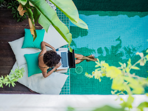 Digital nomad working on laptop by pool