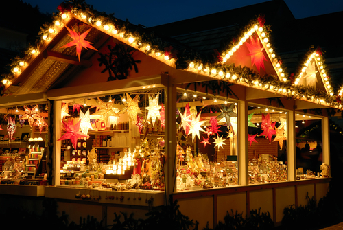 Illuminated Christmas market kiosk with lights strung and decoration merchandise displayed.