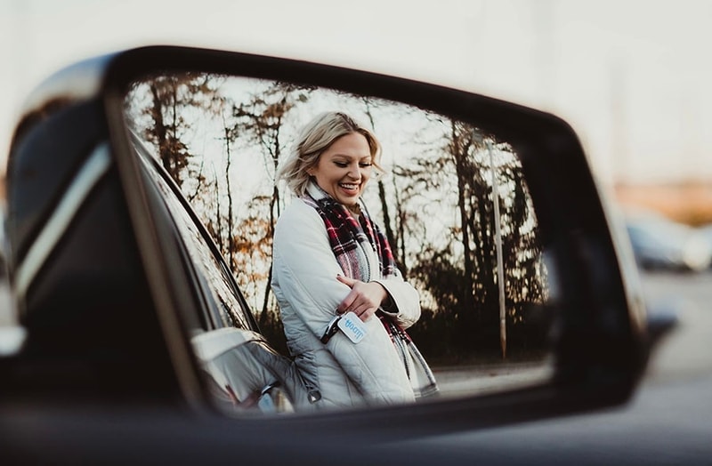 girl leaning on car through mirror