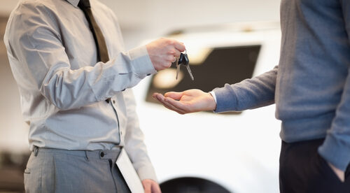 Man handing car keys to another man.