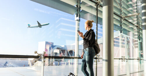 woman standing at terminal window at airport