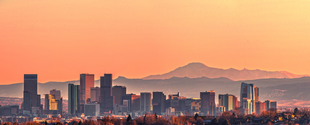 The Denver skyline at sunset, with mountains in the background.