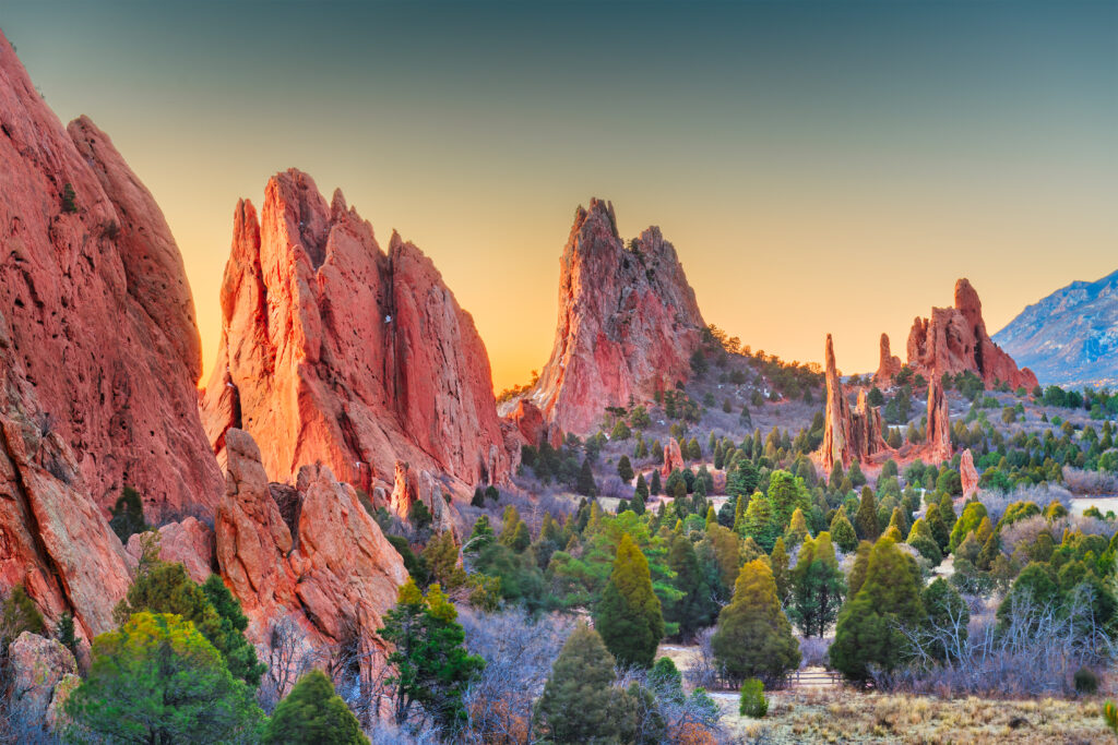 The Garden of the Gods rusted-orange sandstone rock formations surrounded by tree clusters.