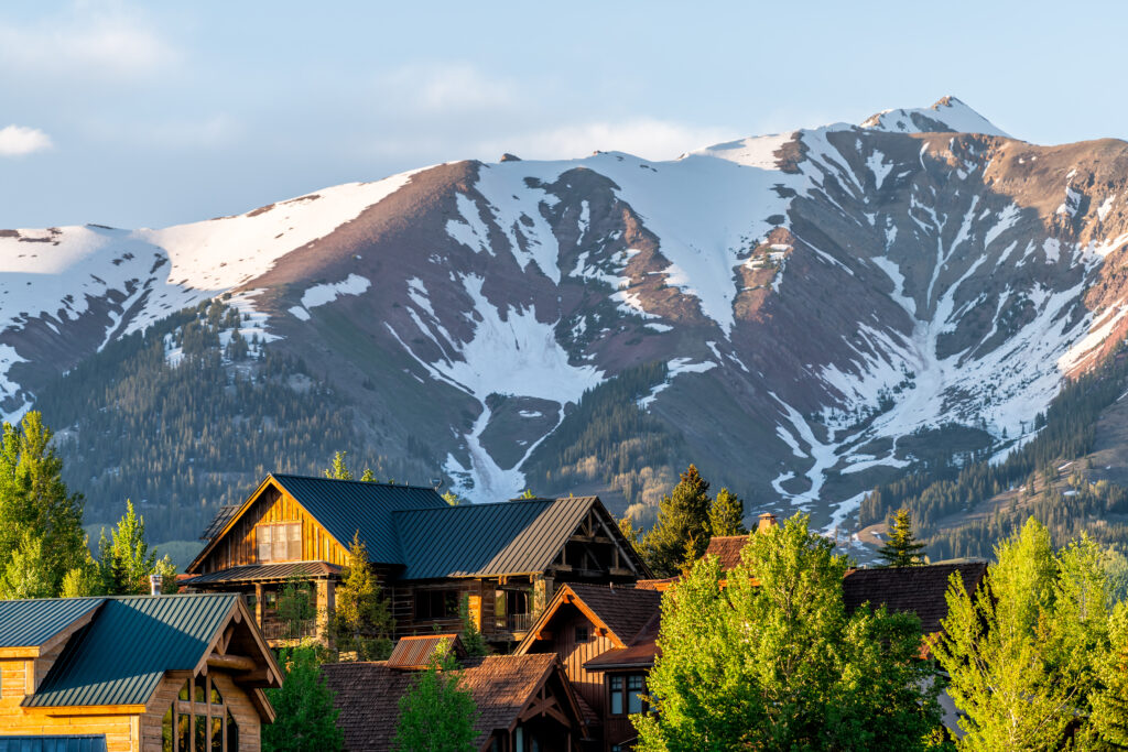 Mount Crested Butte Colorado village houses in summer with colorful sunset on green trees and lodging