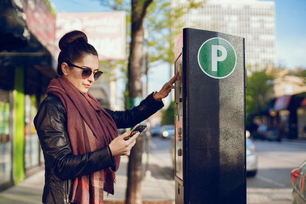woman pays for Parking in meter on the street and parking app