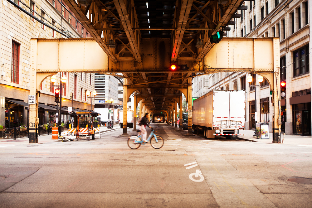 biker passes through an intersection under the L tracks in Chicago.