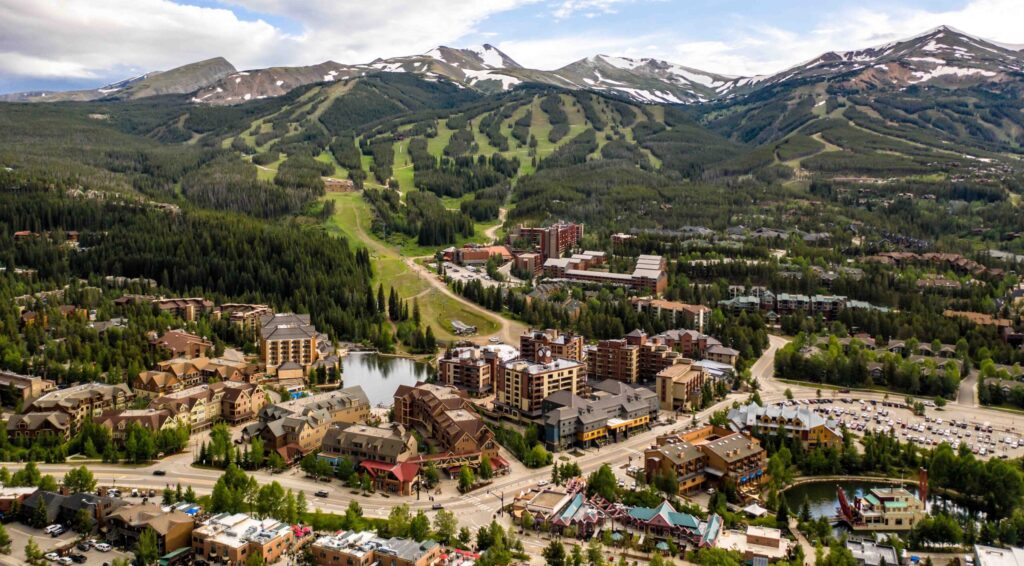 Aerial photo of downtown Breckenridge, Colorado, in summer, with tree-lined mountains in the background.