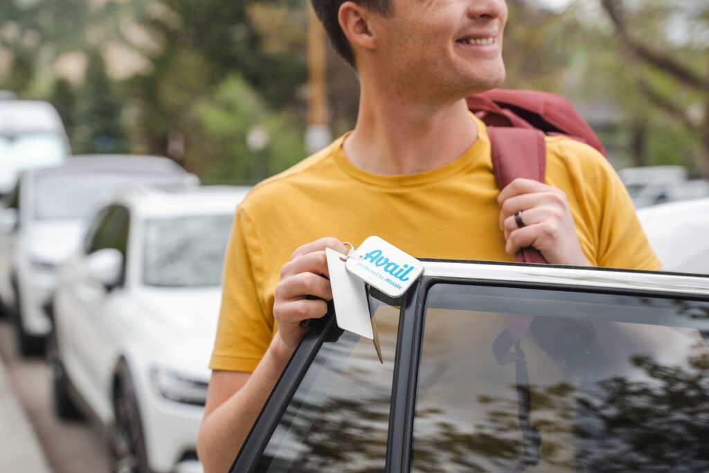 Close up of a smiling man exiting the passenger side of a car